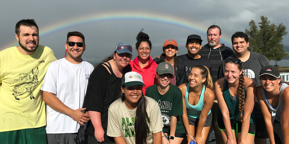 A group of TCBES graduate students pose for a photo under a rainbow.