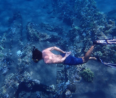John swims over a coral reef while snorkeling