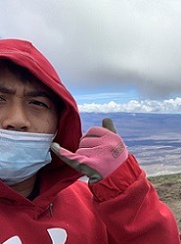 Kimsky stands on top of Mauna Kea and throws a shaka
