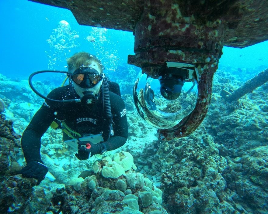 Student diving underwater at a reef with an underwater camera