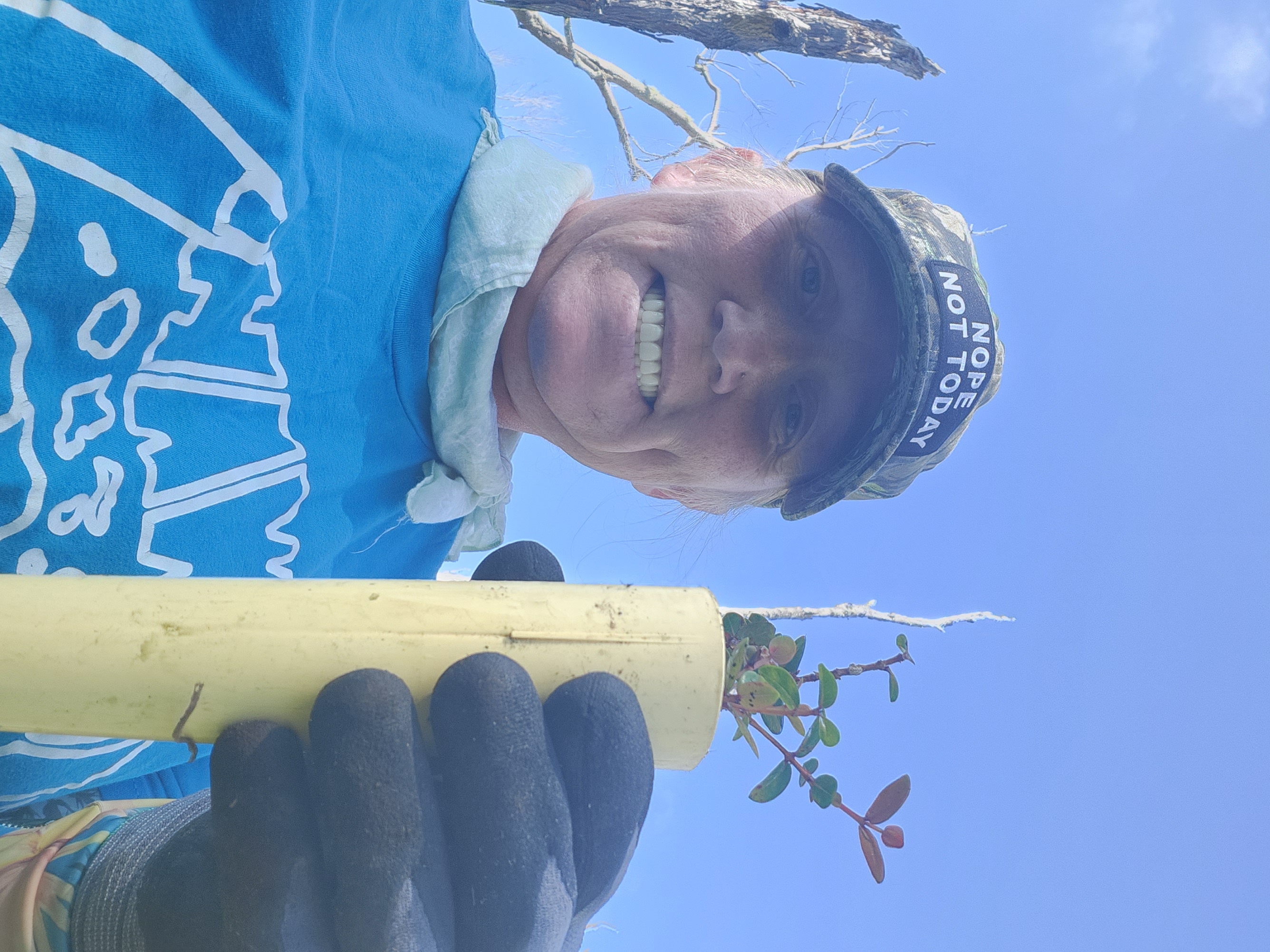 Selfie of Leslie in the field holding a seedling