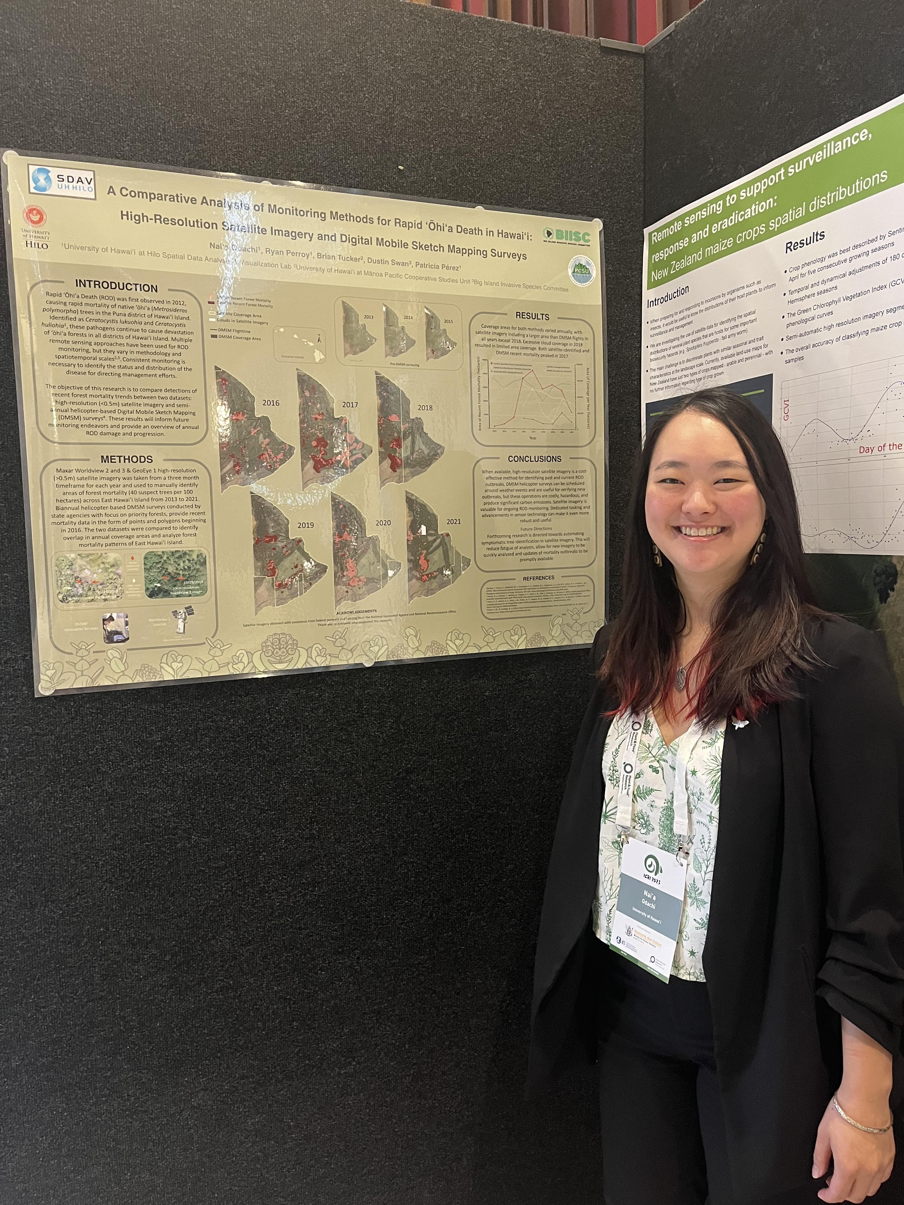Naiʻa, dressed in business attire, stands next to a poster on "A comparaitve analysis of monitoring methods for Rapid 'Ōhi'a Death in Hawaiʻi