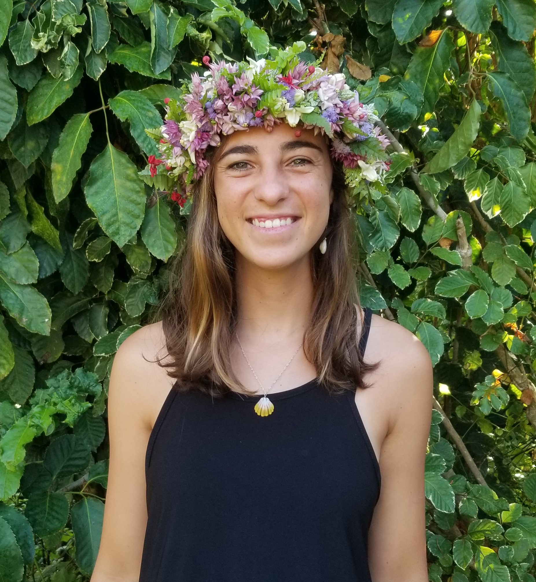 Young woman with light brown hair wearing a flower lei on her head