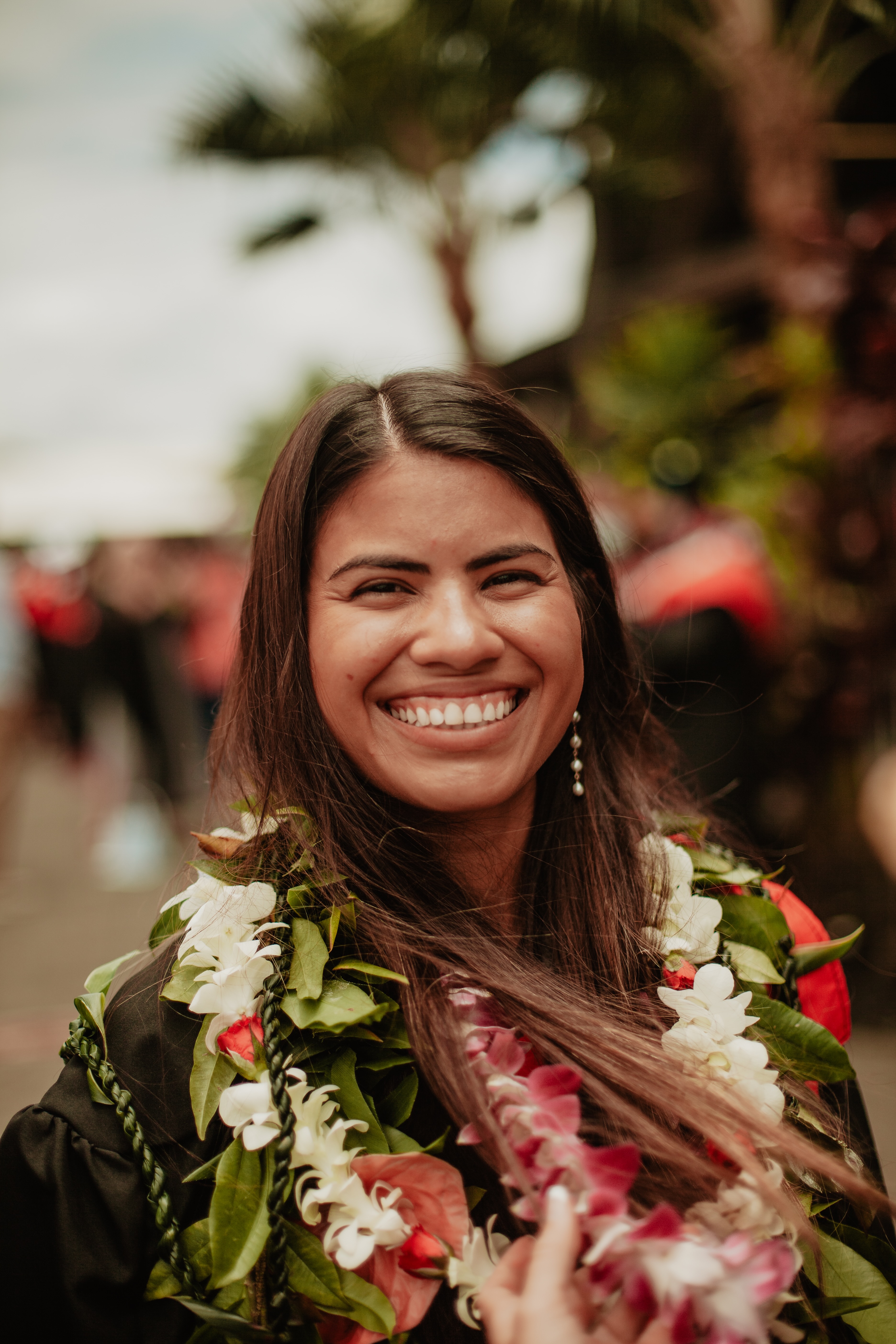 Headshot of Sofia donning several lei after graduation