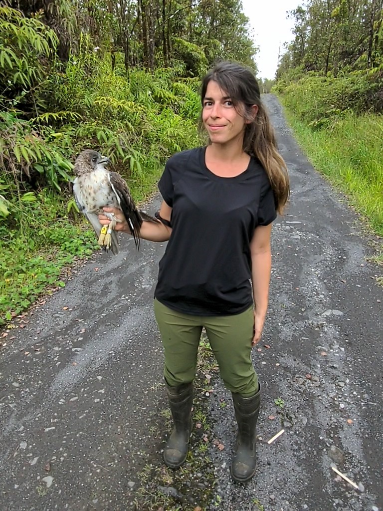 Amy stands on a street holding an 'Io