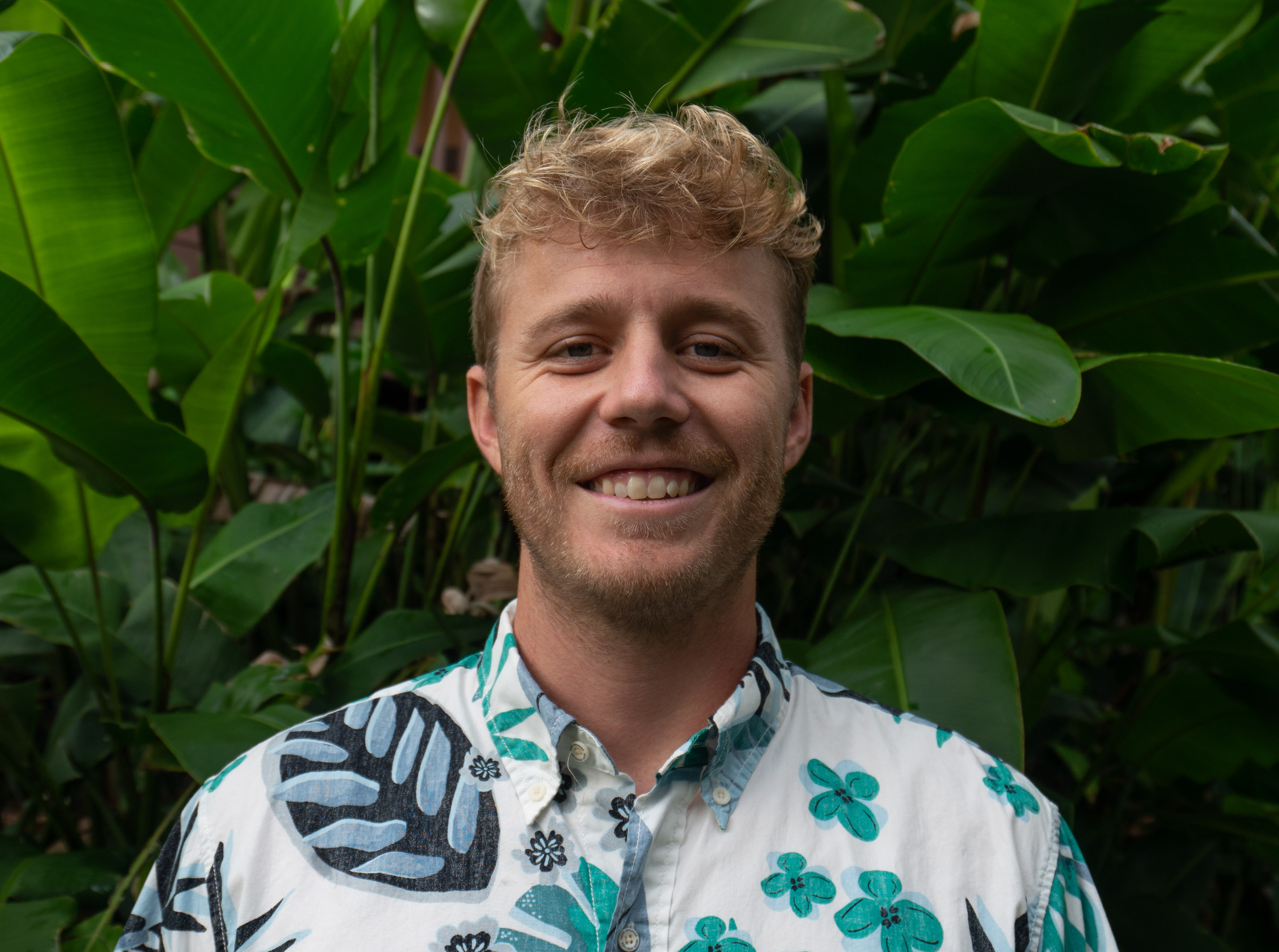 Headshot of Zach standing in front of plants